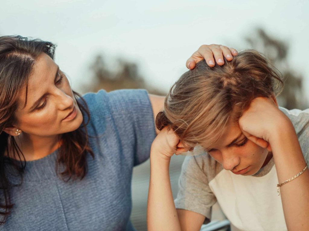 The mother is comforting her son who is lost in thought