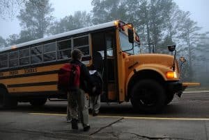 children waiting to board a yellow school bus