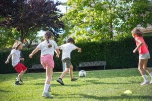 Four children are playing soccer together as an extracurricular activity