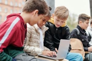 Three children are looking at a computer together
